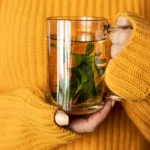 Frau hält Pfefferminztee in der Hand