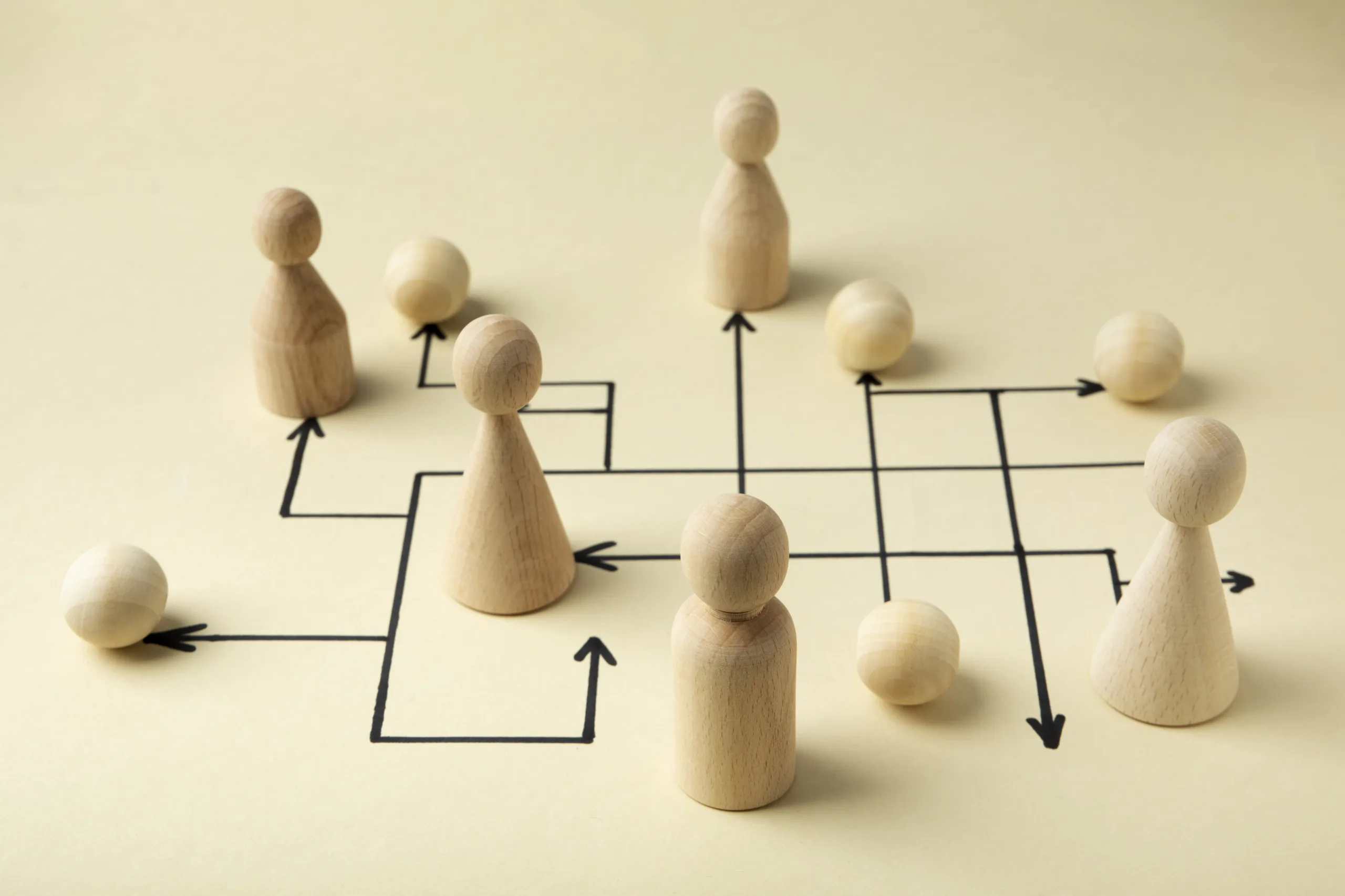 Hölzerne Spielfiguren, auf gedruckten Pfeilen verteilt. Die Pfeile überkreuzen einander.